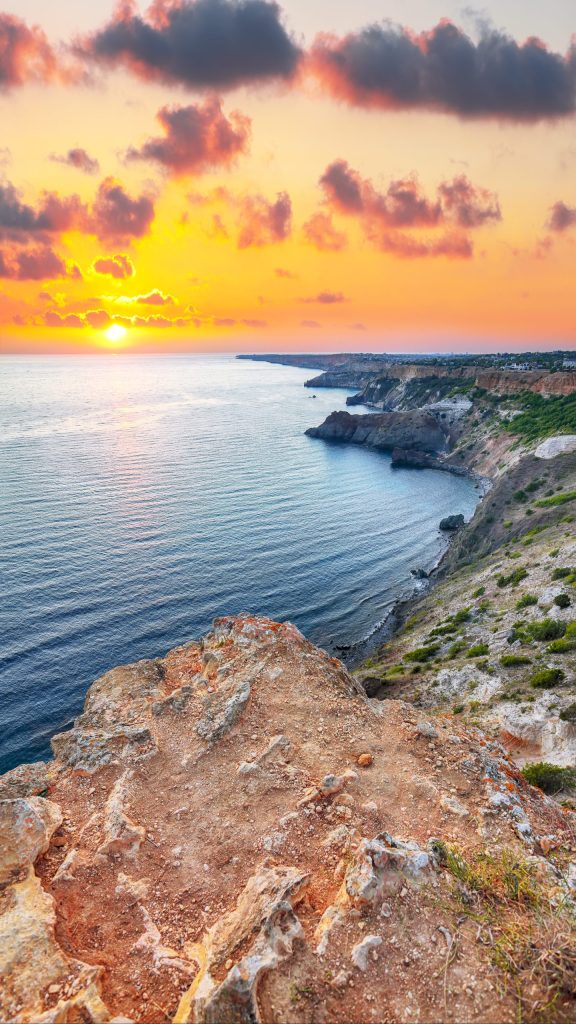 Dramatic sunset at cape Fiolent with bushes grass and rocks at f